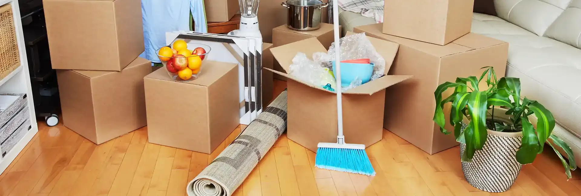 Moving boxes and a broom in a bright empty room